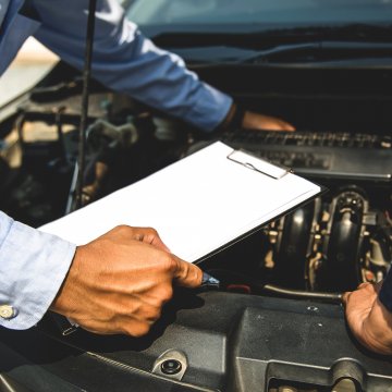 Mechanic with hand under the hood of a car